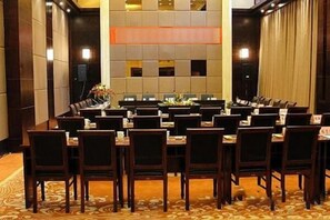 Une salle de conférence dotée de plusieurs tables et chaises, d’un tapis à motifs et d’un décor mural moderne.