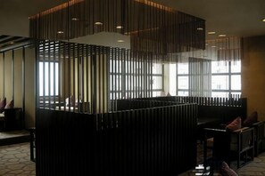 A modern interior with a reception desk, seating area, and large windows allowing natural light.