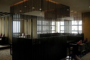 Un interior moderno con mostrador de recepción, zona de estar y ventanas amplias que dejan entrar luz natural.