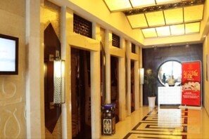 Un hall d’hôtel avec un long couloir, des colonnes, un comptoir d’accueil et une grande fenêtre circulaire.