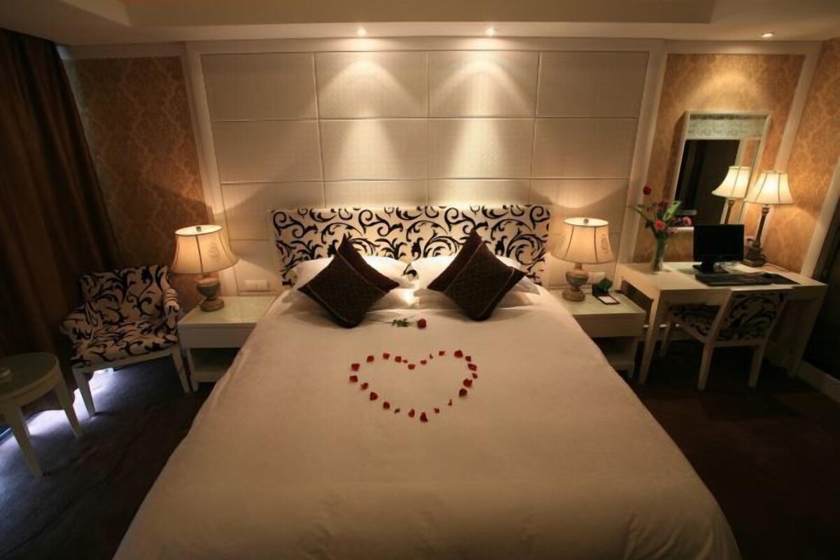 Een hotelkamer met een groot bed, twee nachtkastjes, een bureau en een stoel.