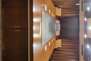 Une salle de conférence équipée d’une grande table, de chaises et d’un pupitre.