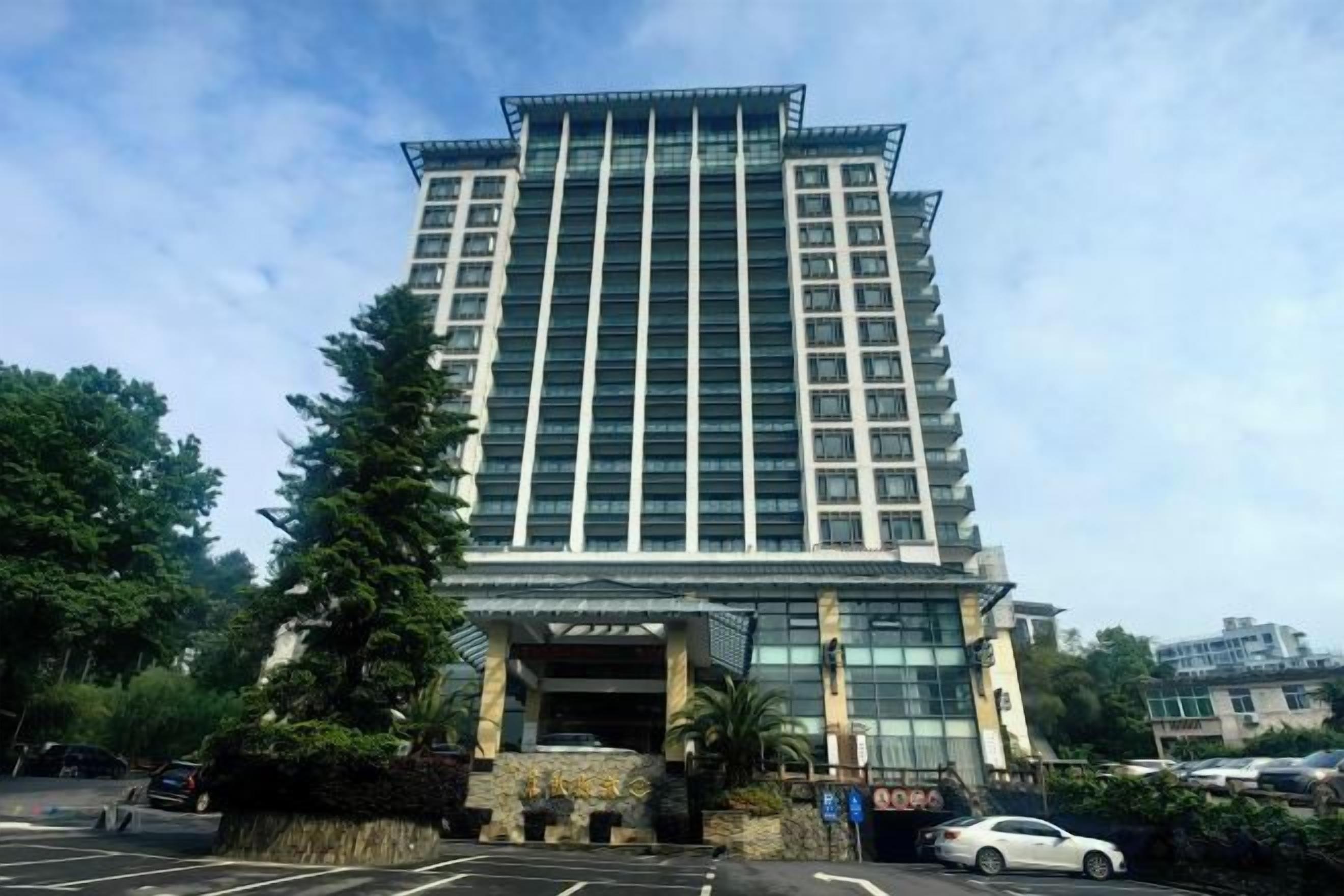 A multi-story hotel with a modern design, featuring a prominent entrance and a parking area in front.