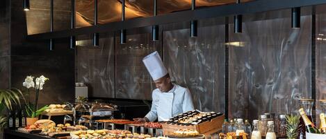 A buffet setup with various food items and a chef preparing food.