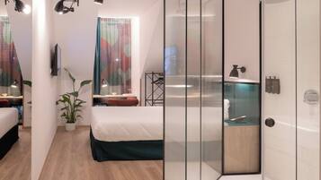 Una habitación de hotel moderna con separador de vidrio, una cama, un escritorio y zona de ducha.