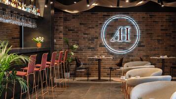 A modern bar area with a neon sign, seating arrangements, and a brick wall.