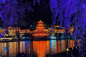 A traditional building with a multi-tiered roof structure, reflecting on the water surface, surrounded by modern buildings.