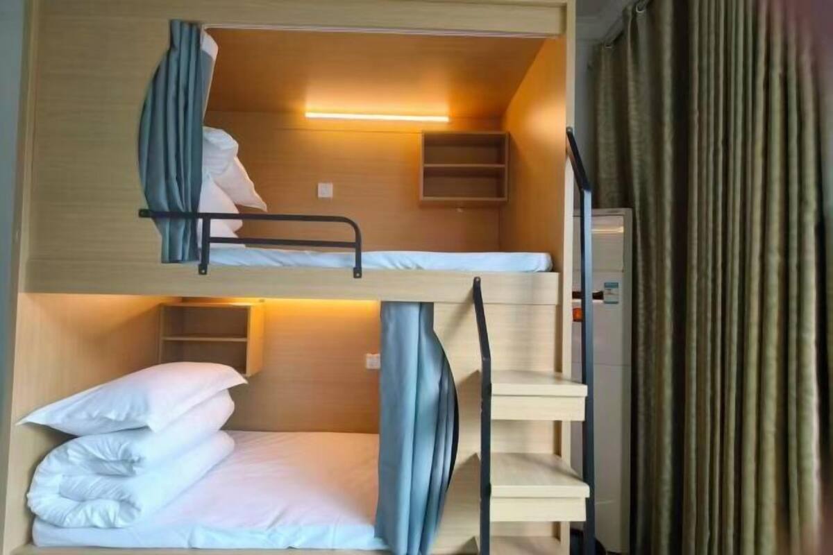 A bunk bed room with a shelf, a heater, and a curtain.