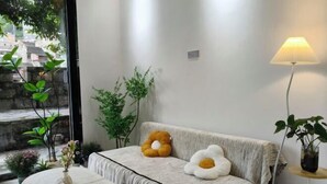 Una habitación con sofá, una mesa redonda y plantas en macetas.