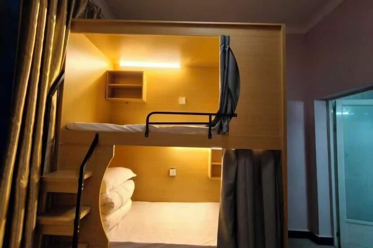A bunk bed room with a small shelf and a bedside table.