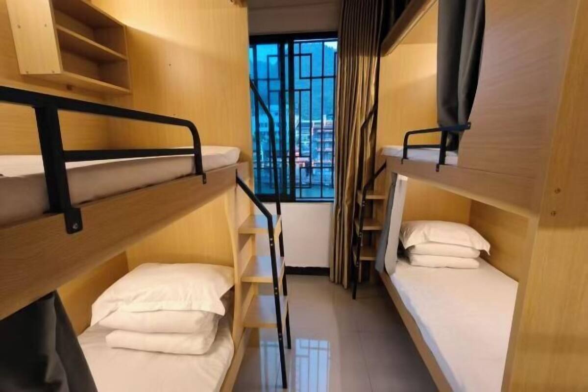 A bunk bed room with a window view, wooden bunk beds, and a small table.