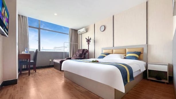 A hotel room with a large bed, a desk, a chair, a TV, and a window with a view. - Kaerlaisi Boutique Stay (Dongguan Chang'an) (Dongguan)