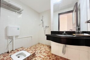 Un baño con inodoro, lavabo, espejo y ducha.