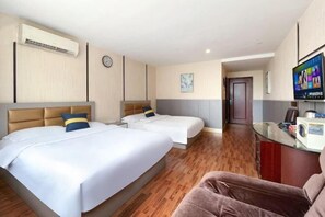 Una habitación de hotel con dos camas, televisión, escritorio y un reloj en la pared.
