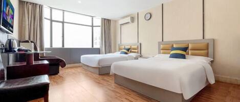 A hotel room with two beds, a desk, a chair, a TV, and a large window.