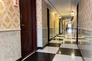 A hotel corridor with checkered flooring, doors, and patterned walls. - Kaerlaisi Boutique Stay (Dongguan Chang'an) (Dongguan)