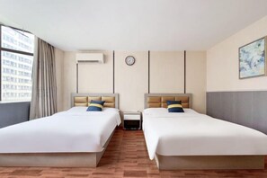 Habitación de hotel con dos camas, un reloj, un aire acondicionado y una ventana con cortinas.