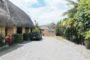 A thatched-roof building with a gravel path leading to it, a parked truck, and a bicycle. - RedDoorz @ Afamosa Villas Resort Ilocos Sur (San Juan)