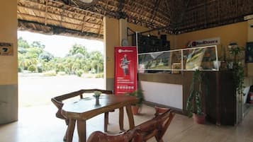 A restaurant with a thatched roof, wooden furniture, and a RedDoorz sign.