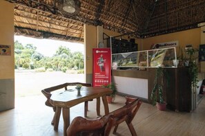 A restaurant with a thatched roof, wooden furniture, and a RedDoorz sign. - RedDoorz @ Afamosa Villas Resort Ilocos Sur (San Juan)