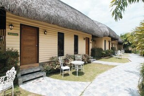 A row of thatched-roof cottages with outdoor seating and a paved walkway. - RedDoorz @ Afamosa Villas Resort Ilocos Sur (San Juan)