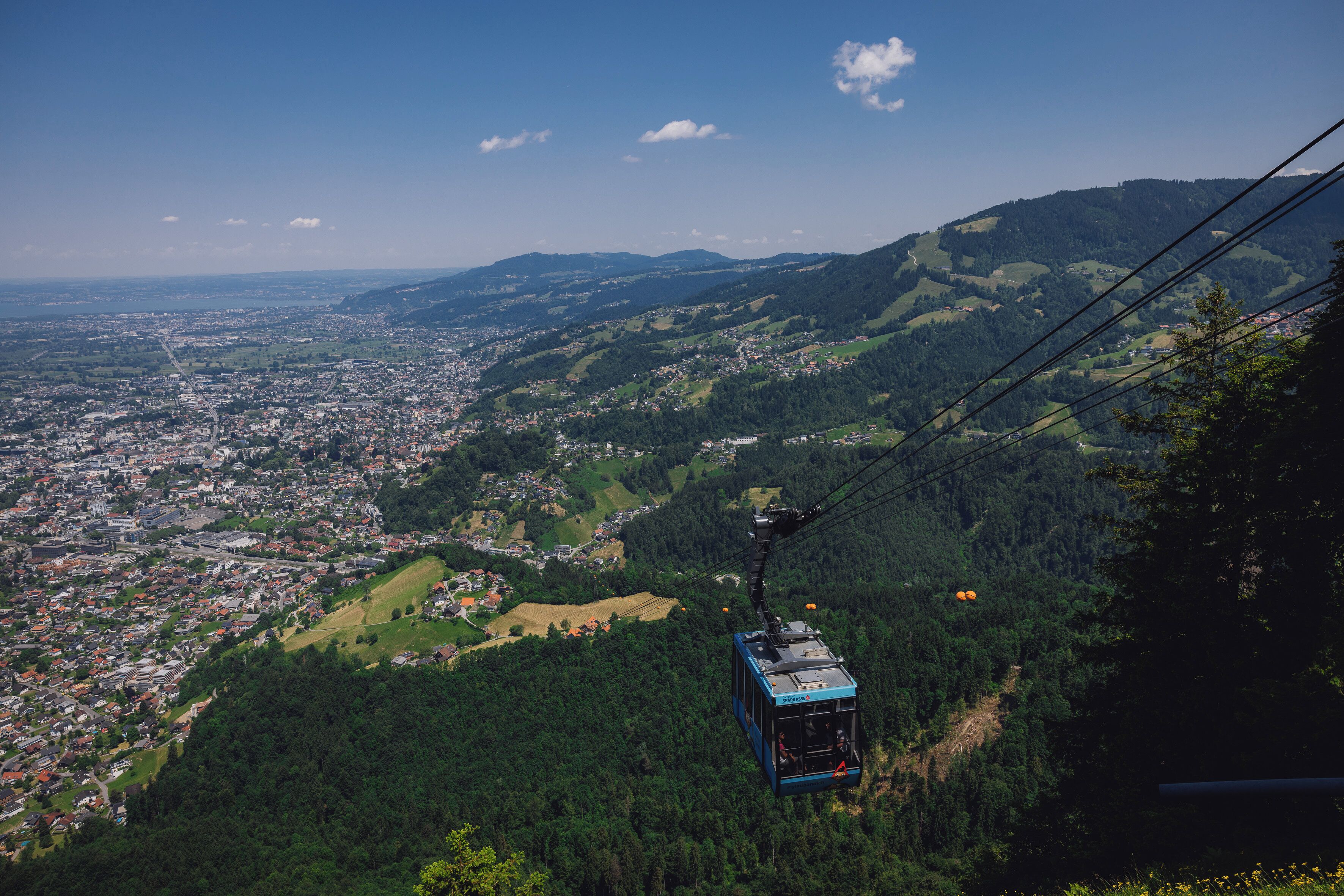 A cable car moving over a mountainous landscape with a town below.