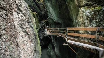 Eine Holzbrücke über einer schmalen Schlucht mit steinernen Wänden und einem Fluss darunter.