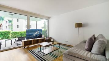 Een moderne woonkamer met een grote televisie, een bank, een salontafel en een vloerlamp.