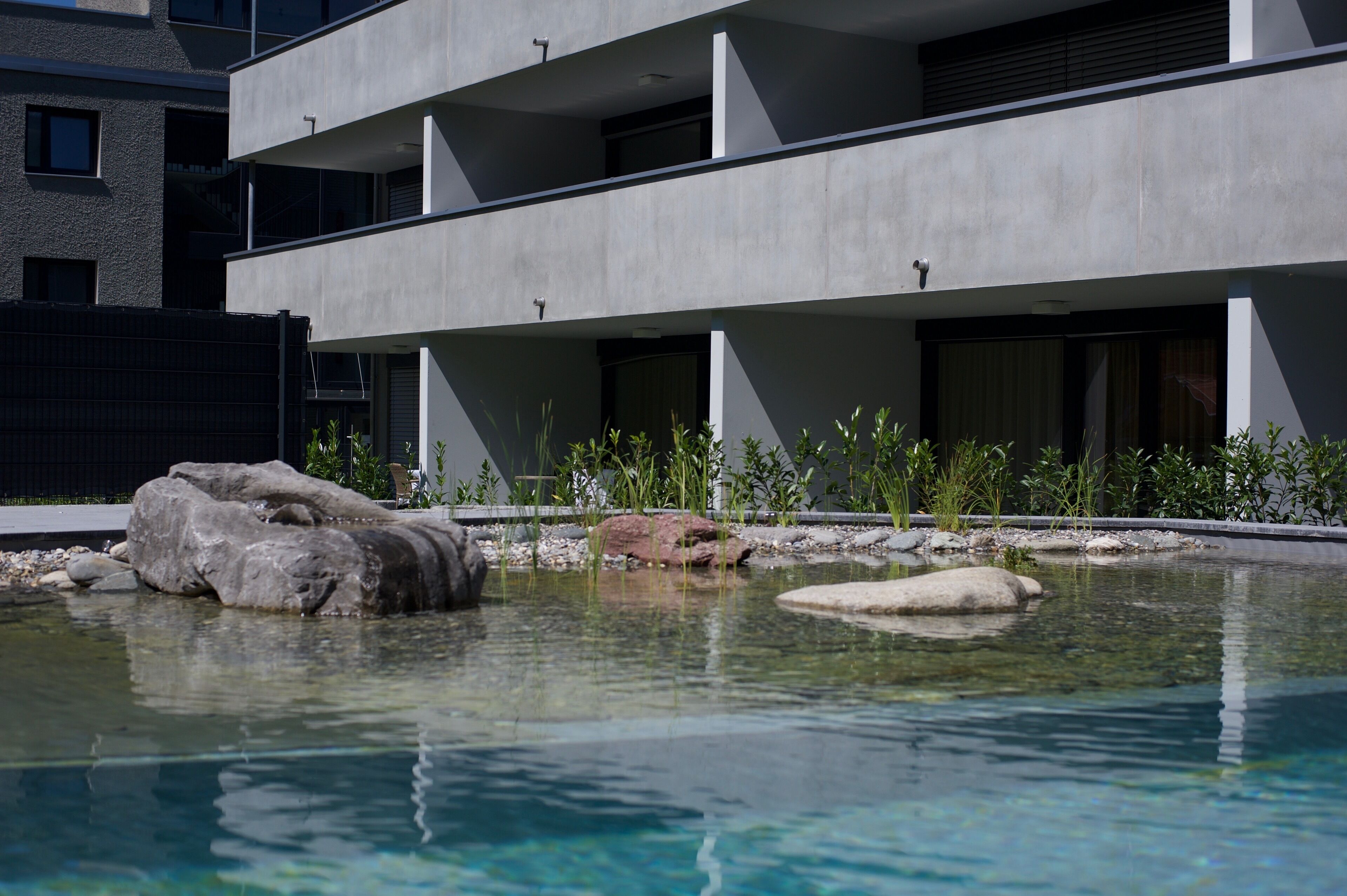 Um edifício moderno com área de piscina, pedras e plantas.