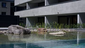 Um edifício moderno com área de piscina, pedras e plantas.