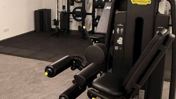 A gym with a bench press, squat rack, and various weight plates.