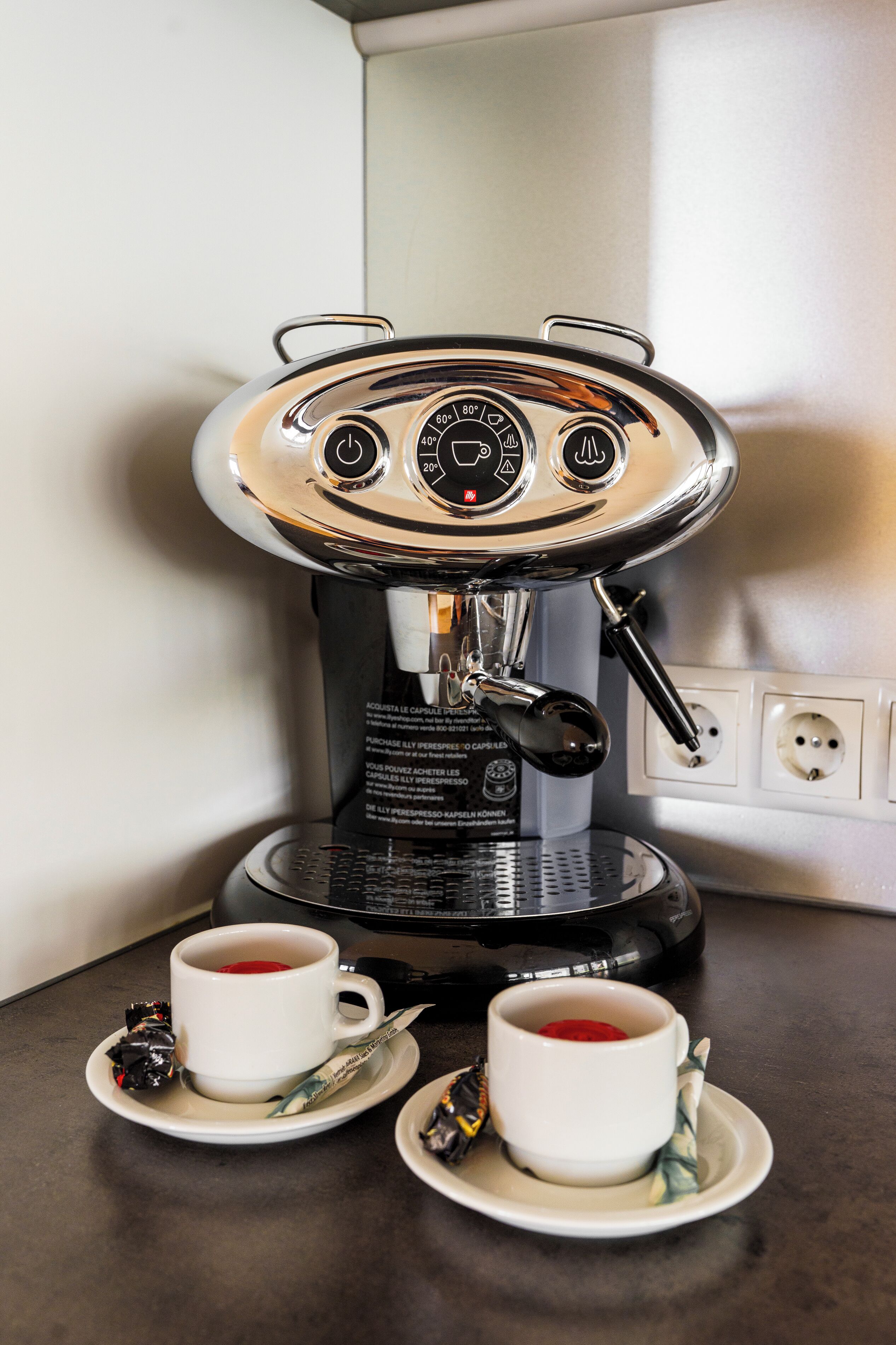 A coffee machine with two cups of coffee on a table.