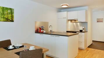 A modern kitchen with white cabinets, a central island, and a dining area with a table and chairs.