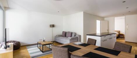 A modern living room with a sofa, a coffee table, and a dining area with a table and chairs.