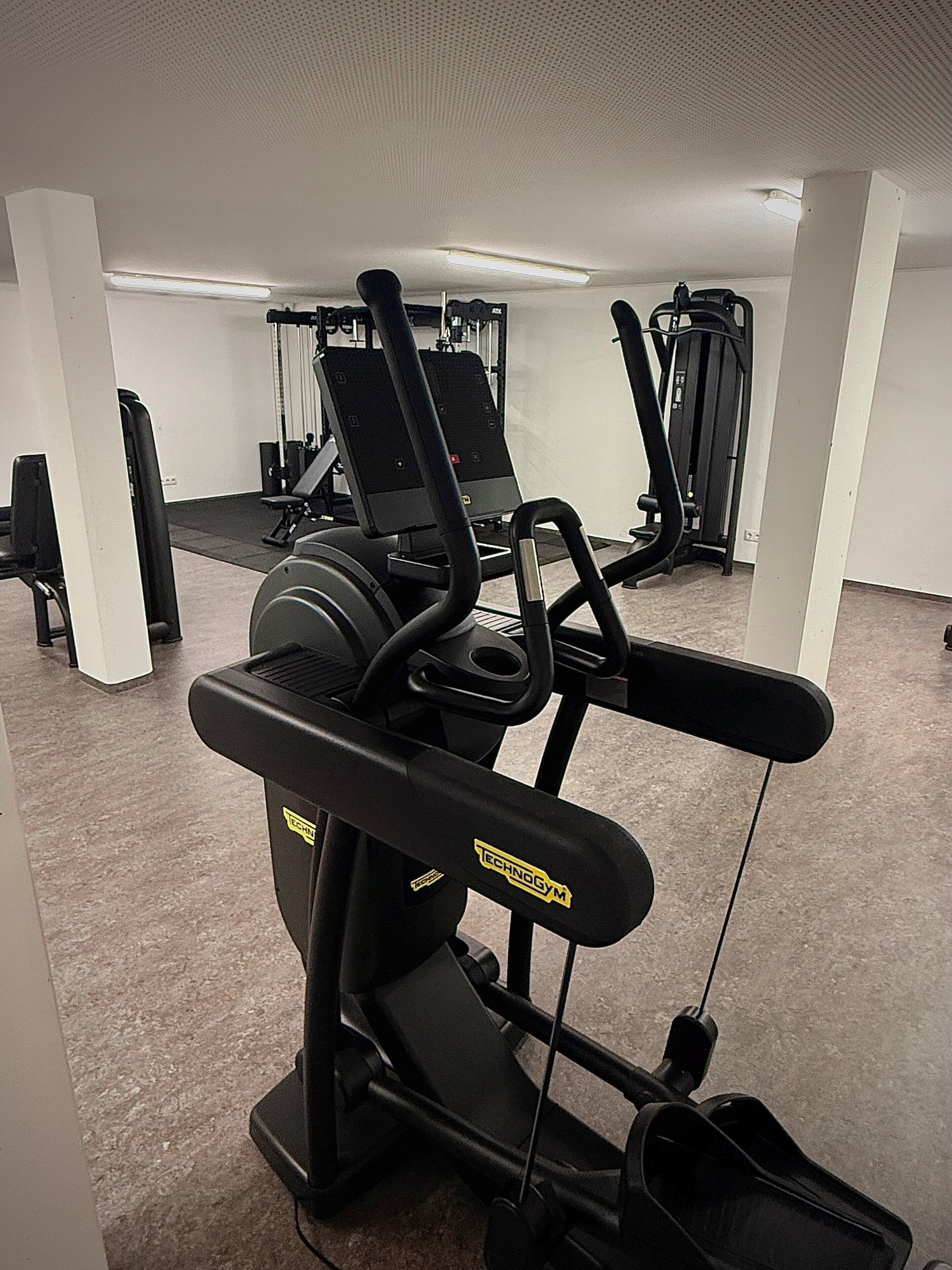 Un gimnasio con equipo cardiovascular, que incluye cintas de correr y máquinas de pesas.