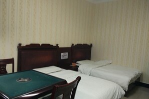 Ein Zimmer mit zwei Einzelbetten, einem Holztisch mit grüner Tischplatte und einem Stuhl.