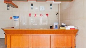 A reception desk with a wooden finish, a clock, and a sign with Chinese characters. - Fuling Sifang Hotel (Liling)