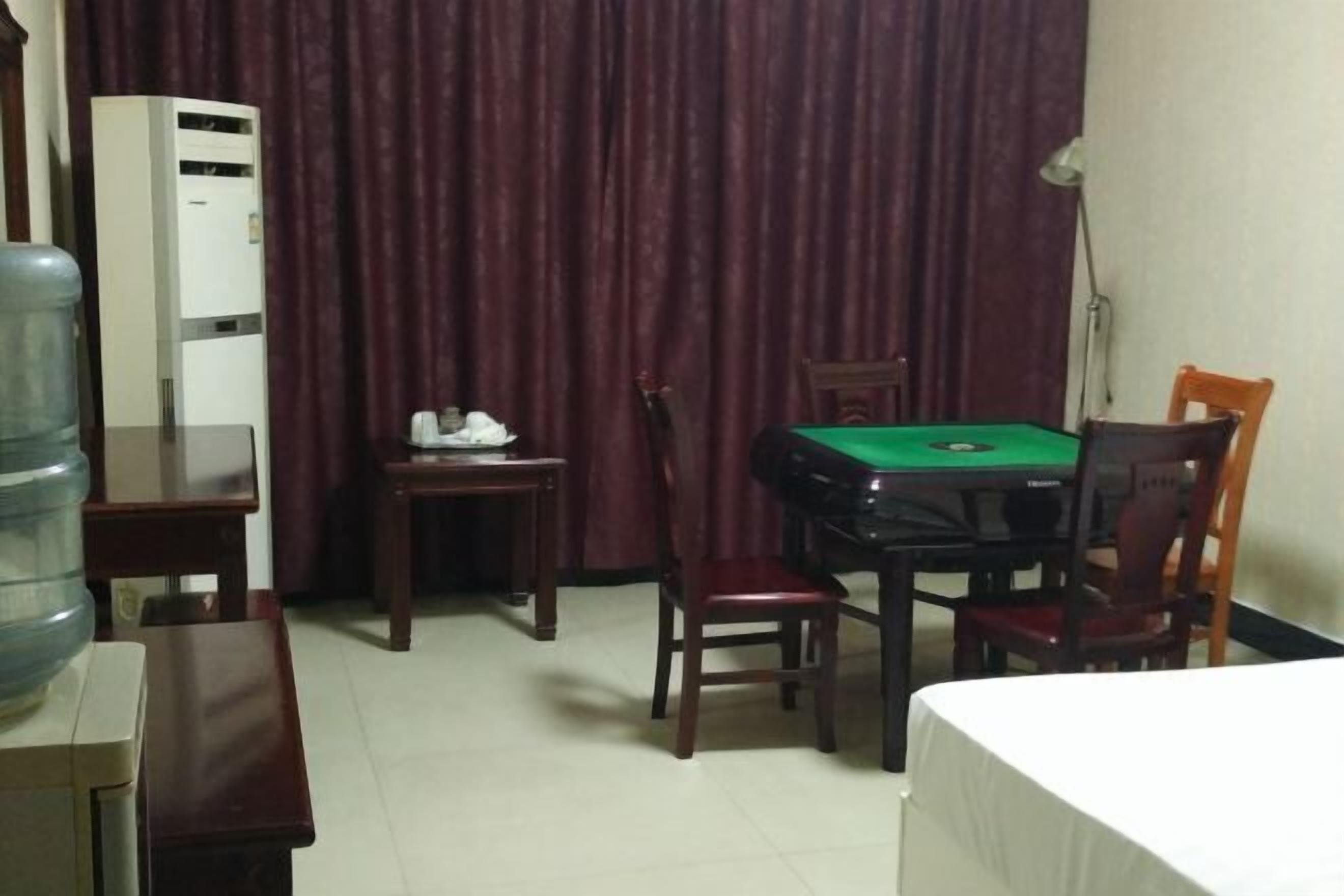 Habitación de hotel con mesa de billar verde, dispensador de agua, escritorio y cama.
