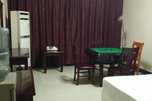 Ein Hotelzimmer mit grünen Billardtisch, Wasserspender, Schreibtisch und Bett.