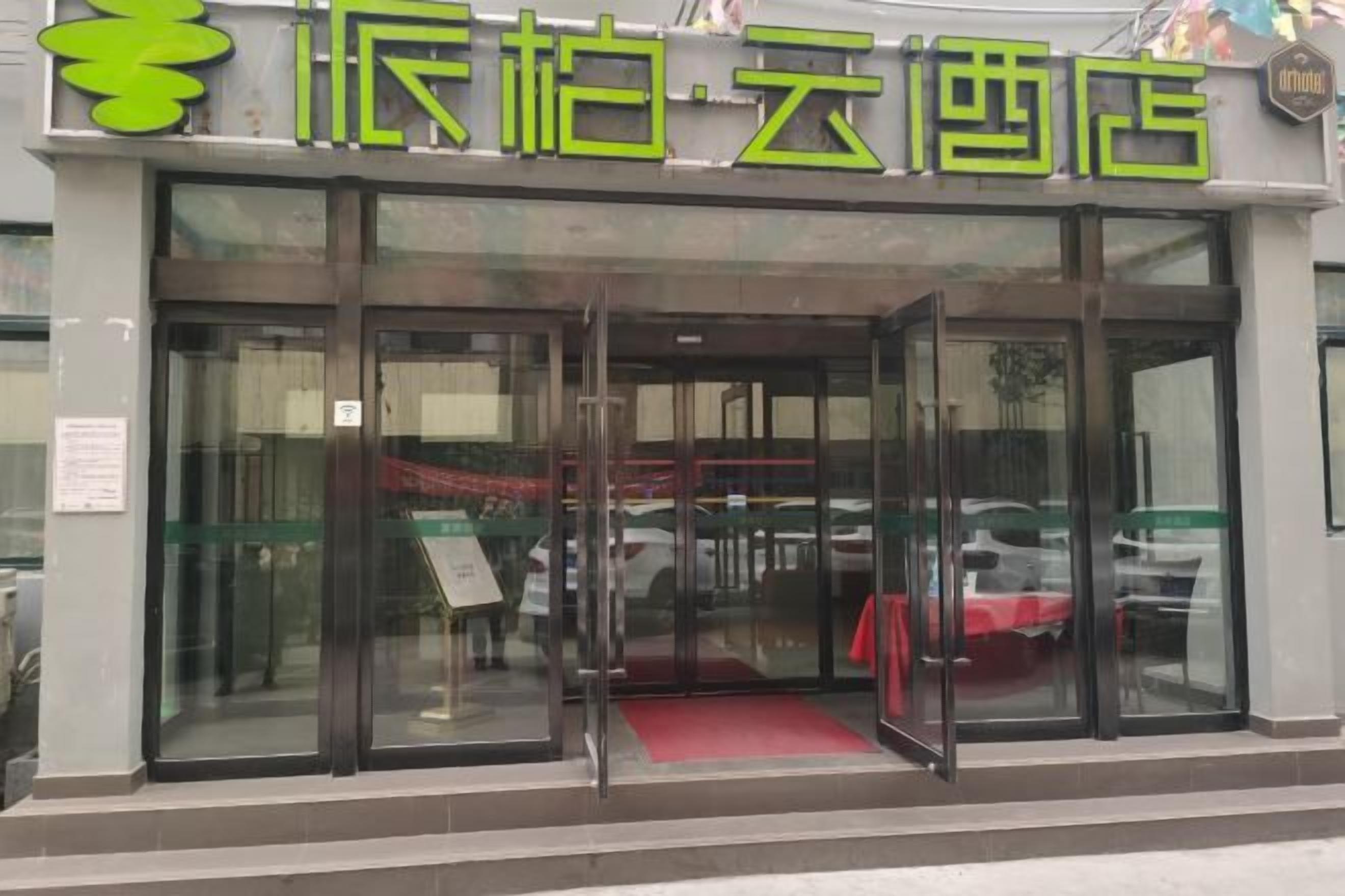 A hotel entrance with glass doors and a red carpet.
