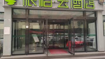 A hotel entrance with glass doors and a red carpet.