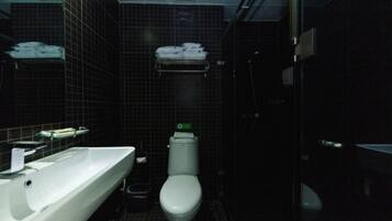 A small, dark bathroom with a white sink, a toilet, and a mirror.
