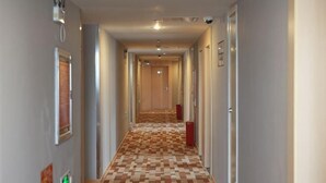 Ein Hotelgang mit Schachbrettfußboden, Türen auf beiden Seiten und einer hellen Wand.