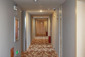 A hotel hallway with a checkered floor, doors on both sides, and a light-colored wall. - Homeinn Pebble Hotel (Zhengzhou Jinshui Road Medical College) (Zhengzhou)