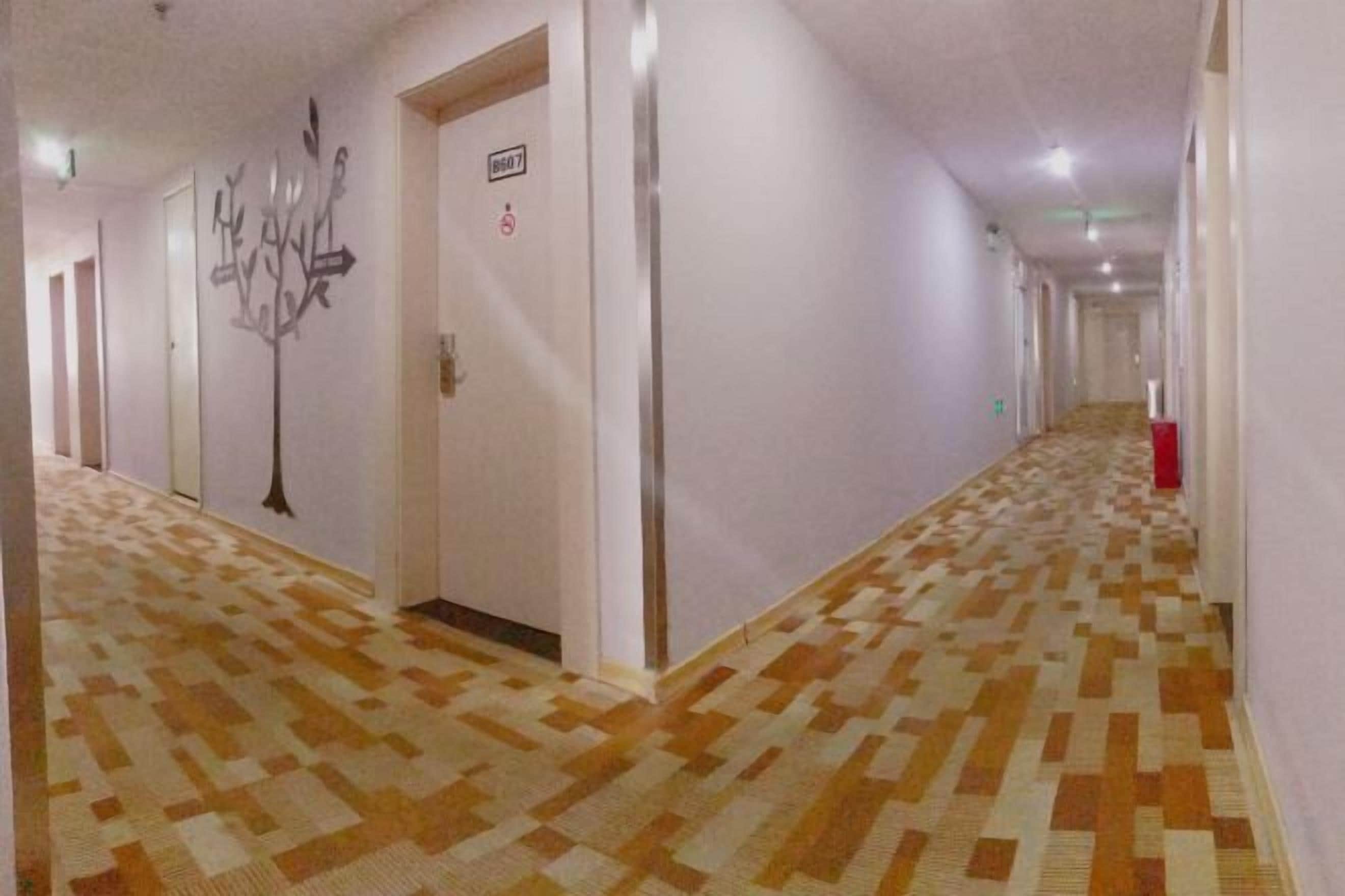 Ein Hotelgang mit gemustertem Boden, Türen und einem an der Wand befestigten Schild.