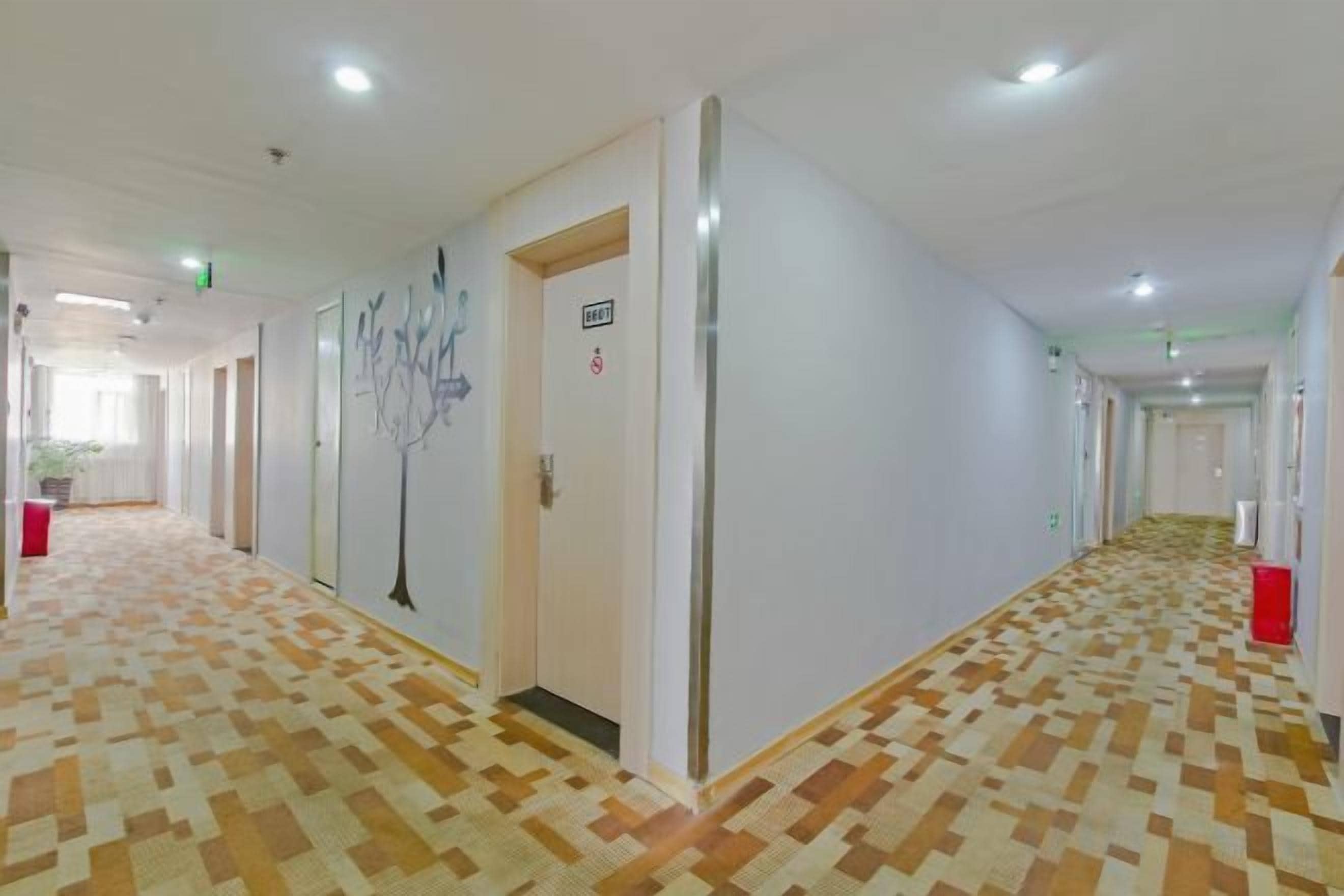 A hotel corridor with patterned flooring, doors, and a wall-mounted sign.