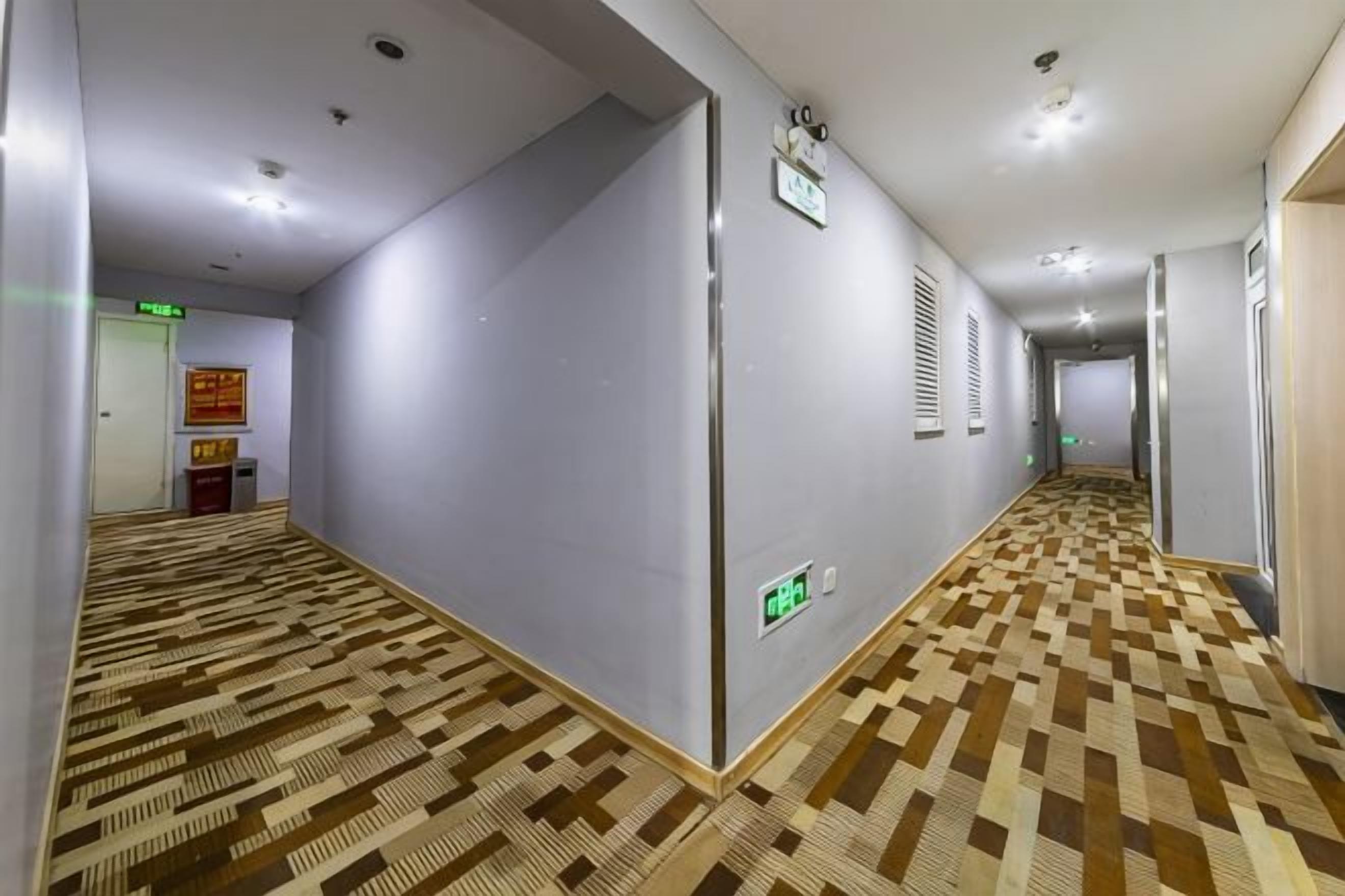 Ein Hotelgang mit gemustertem Boden, einem Rauchmelder und einem Notausgangsschild.