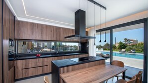 Een moderne keuken met een groot eiland, inbouwapparatuur en uitzicht op een zwembad.