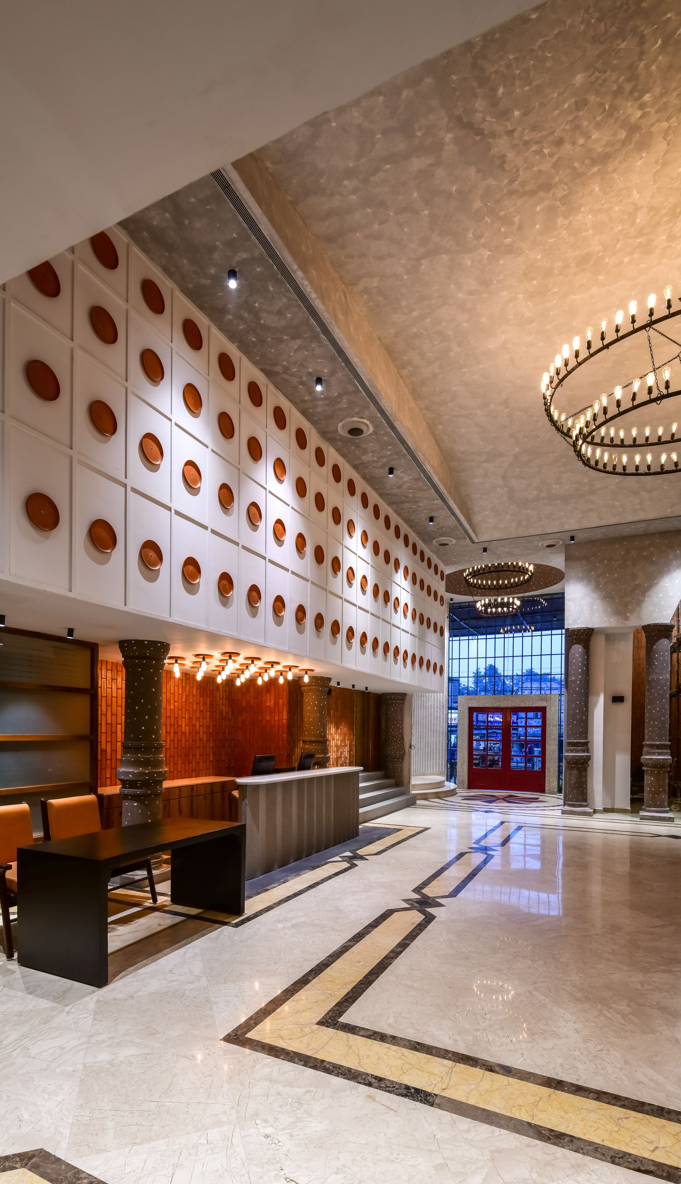 A spacious lobby with a reception desk, patterned walls, and a marble floor.