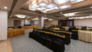 Une salle de conférence avec des rangées de chaises, des tables et un tapis à motifs.